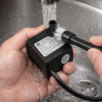 Nettoyage de la pompe pour fontaine à eau chat sous l’eau avec brosse